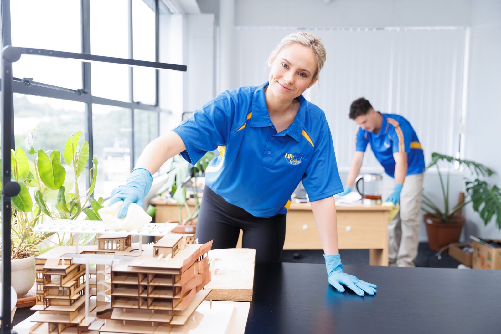 Cleaner wiping a desk in a bright office